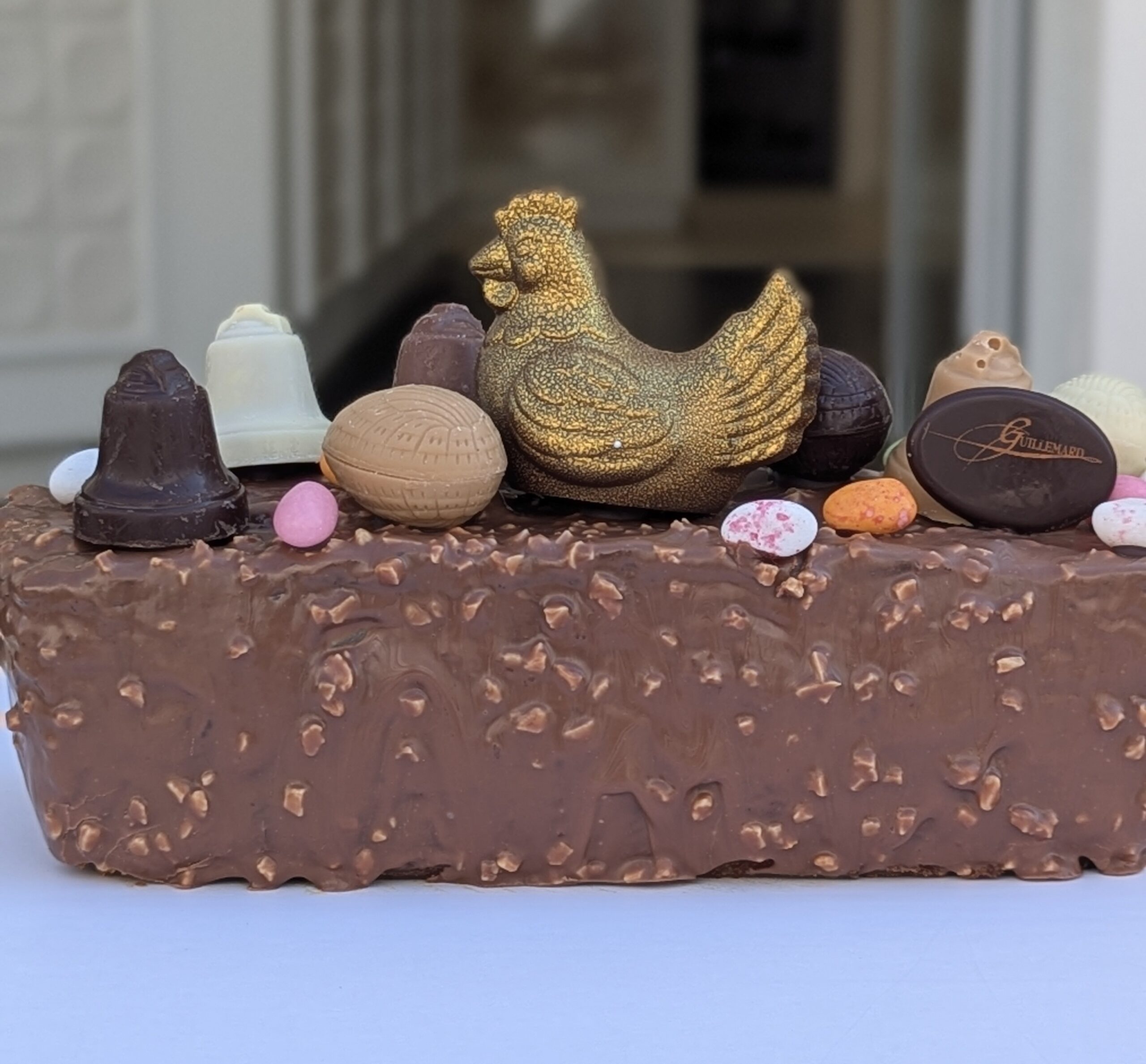 cake de paques , vanille aux notes d'agrumes, confits (orange et citron) aux pepite de chocolat et aux éclats de noisette. enrobé chocolat lait aux éclats d'amande grillées